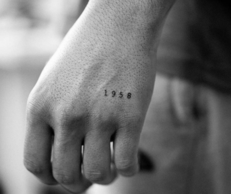 Tatuaje minimalista de fecha en la mano