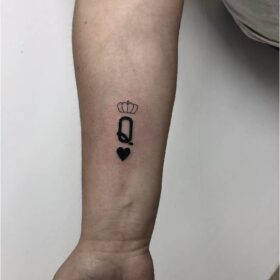 tatuaje pequeño de letra queen en antebrazo con corazon minimalista