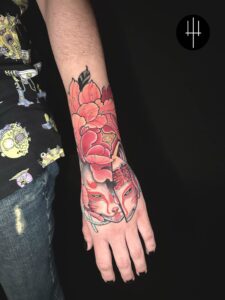 tatuaje mascara y flor peonia en antebrazo y mano